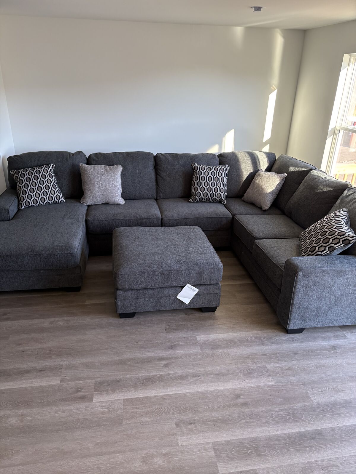 Gray sectional sofa with matching ottoman and accent pillows in a living room